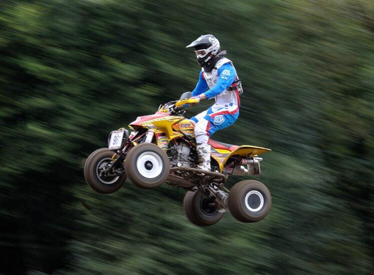 Part of a series for a Quad Motocross National Champion, demonstrating his amazing (and fearless) ability to catch air at 60+ mph. In sharp focus against a motion-blurred background. © Jerry and Lois Photography, all rights reserved